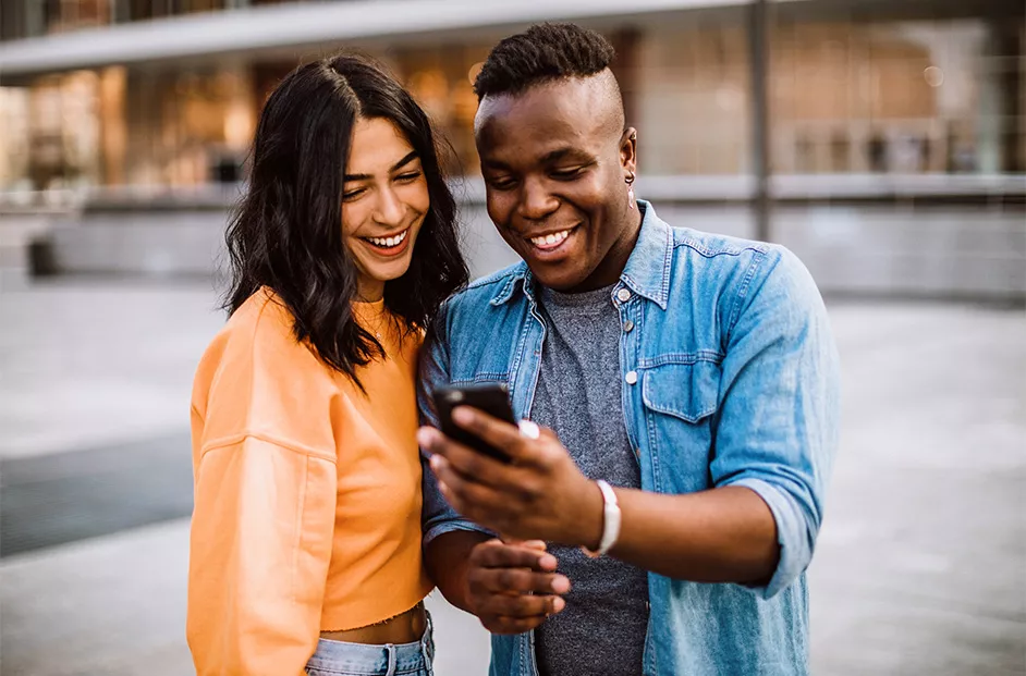 Woman and man smile while look at a cell phone