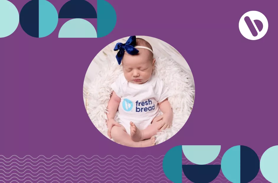 Sleeping baby pictured with a bow on her head while wearing a "Fresh Bread" onesie.