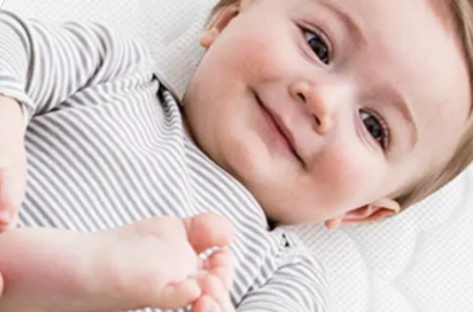 Smiling baby holding its foot