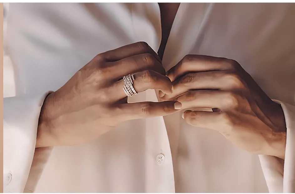 woman wearing necklace, two blue packages and a women buttoning her shirt wearing a ring