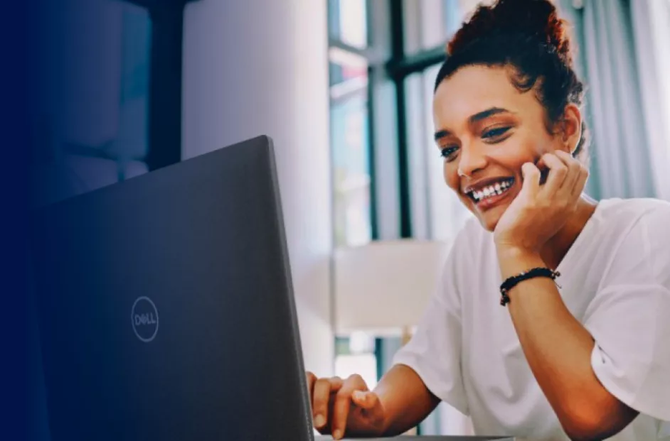 A woman smiles while using her Dell laptop.