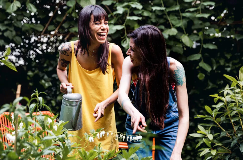 Two female friends laughing while working in the garden.