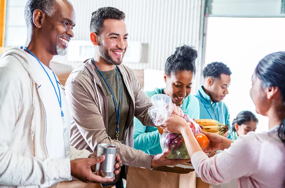 A group of friends volunteers at a food bank.