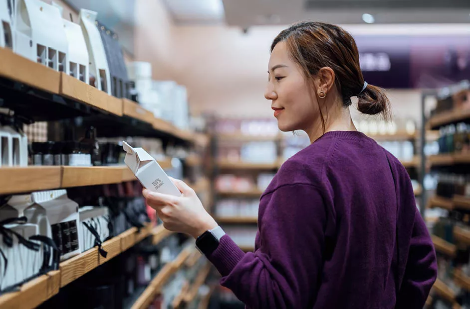 Woman shopping, picking an item off the shelf.