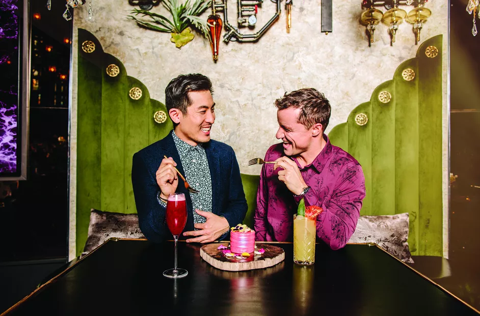 Two men enjoy cocktails and desert at a high-class restaurant.