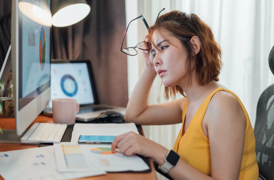 Asian woman appears stressed while calculating money expenses and planning a budget from her computer at home