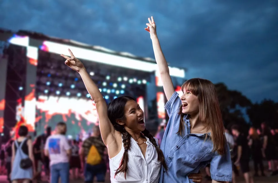 Two female friends of Asian and Caucasian ethnicity enjoying the atmosphere at a music festival. 