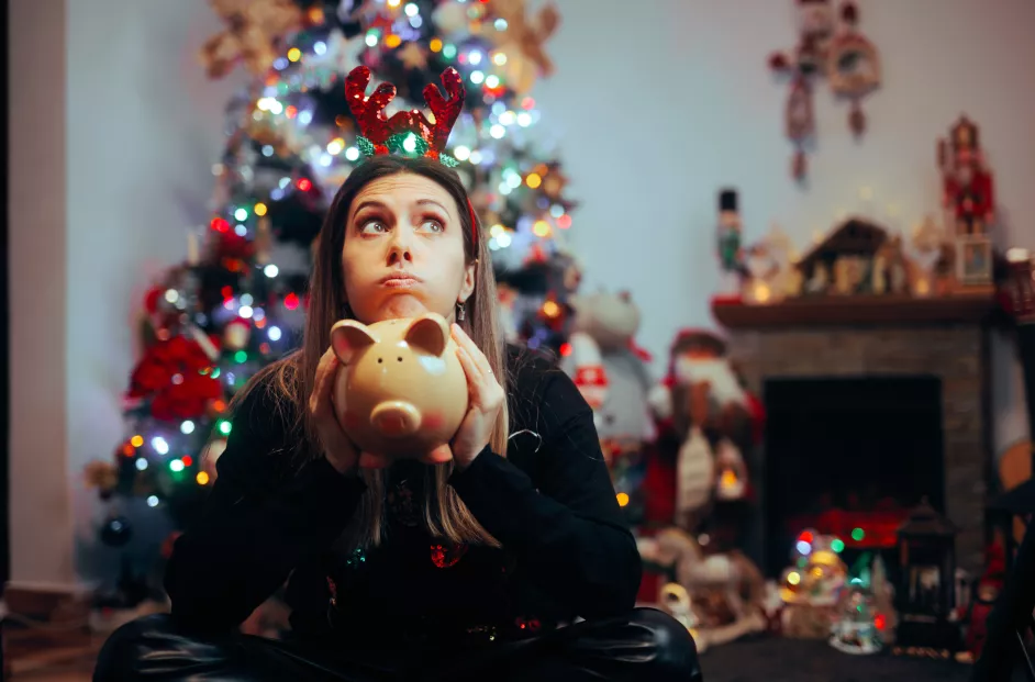 Stressed young woman holding a piggy bank and regretting holiday spendings
