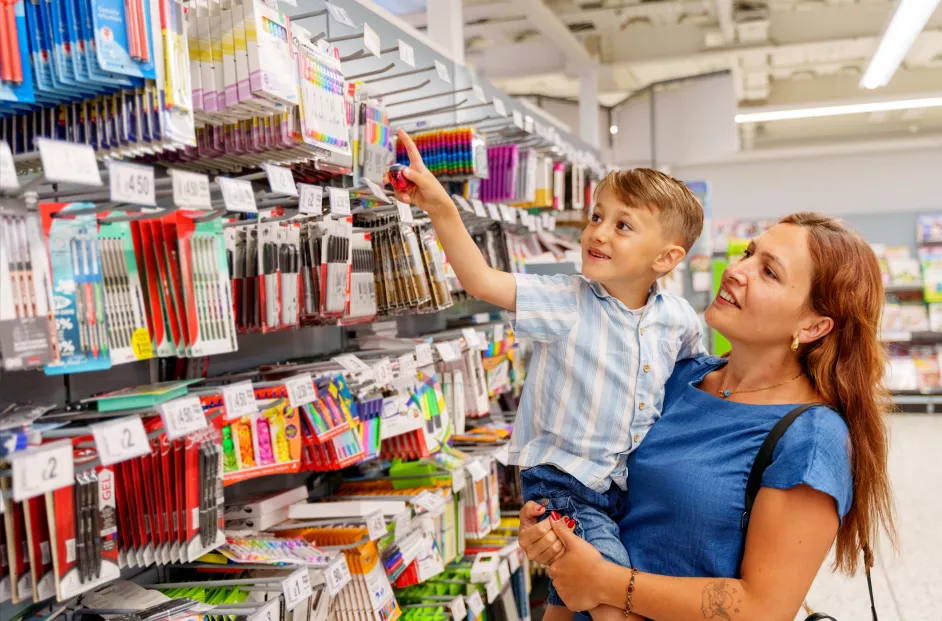 A child excitedly shopping for stationery on his mother's lap