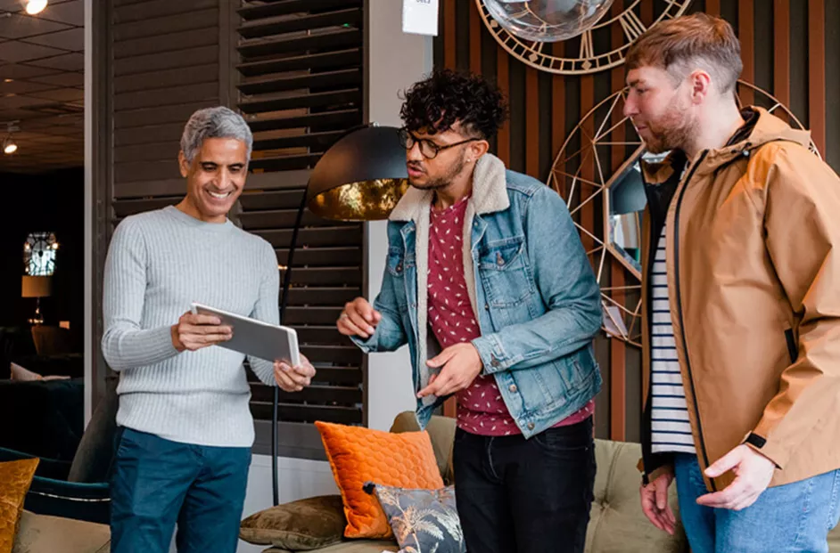 Three men looking at information on an ipad smiling