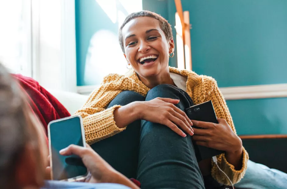 woman smiling and being affectionate while sitting on the couch with another person
