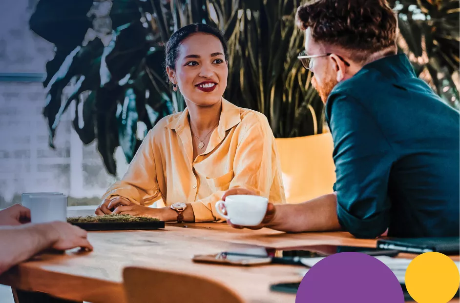 Stock image of a man and women having a meeting at a table. Includes the text "2024 Sustainability Report", the Bread Financial logo and bauhaus elements.
