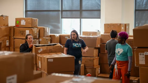 Bread Financial associates sort through boxes of clothing donations from Maurices.