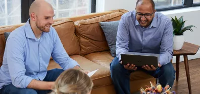 Two men sitting on a couch looking at laptops