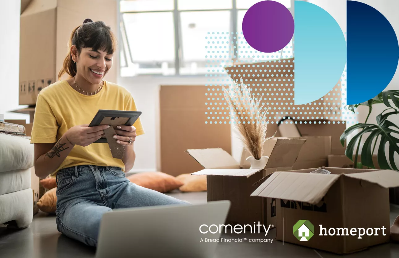 Woman smiles while holding a photo and unpacking boxes in her new home. 