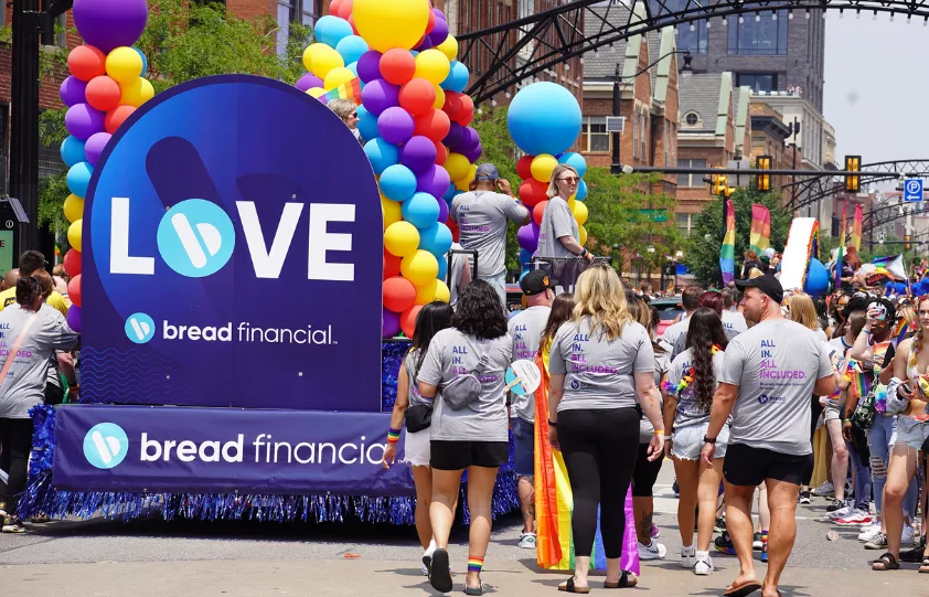 Bread Financial associates walking in the Columbus Pride Parade. Featured in the photo is the company's float, featuring the words in bold, capital letters.