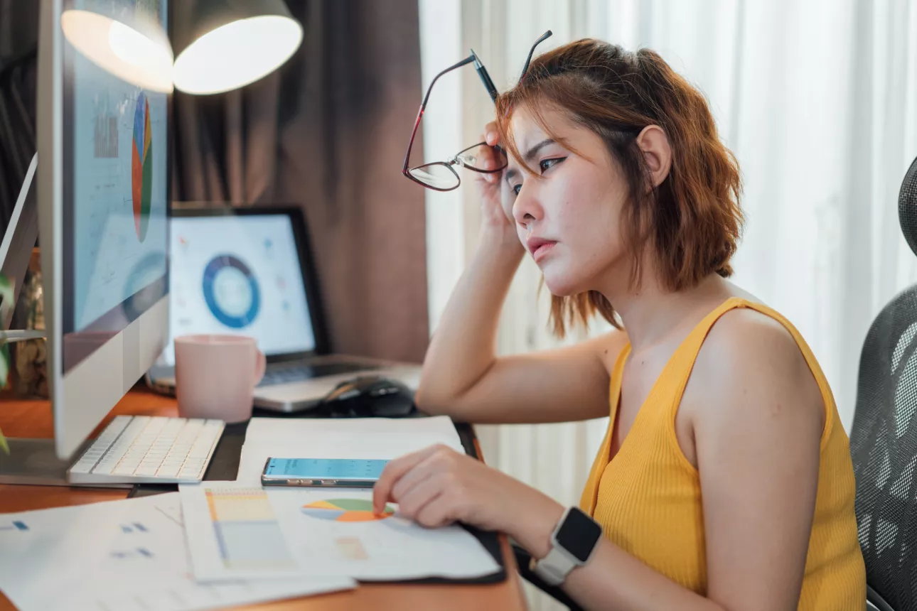 Asian woman appears stressed while calculating money expenses and planning a budget from her computer at home