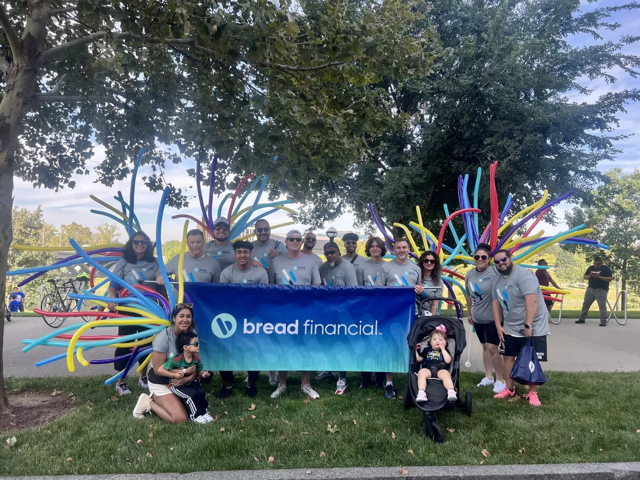 Group photo with Bread Financial sign after a parade. 